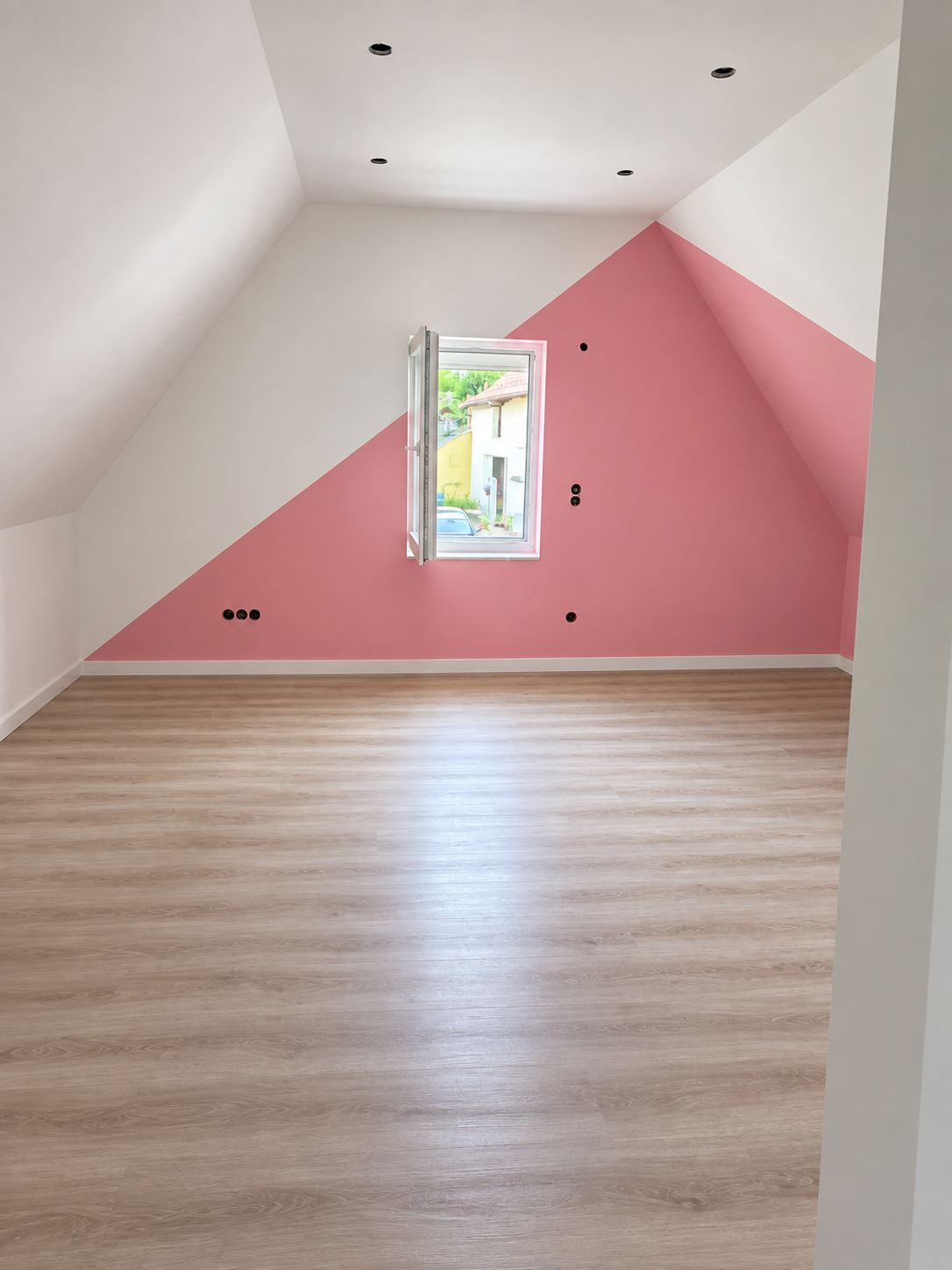 Ausgebautes Dachzimmer mit Dachschrägen, Einbauspots und Fenster in der Giebelwand