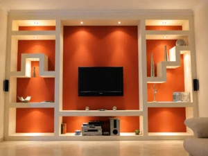 Fertige TV-Wand in Trockenbauweise mit beleuchteten Regalnischen und orangefarbener Rückwand